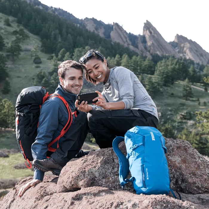 pareja tomandose una foto en la montaña posando con su mochila thule alltrail