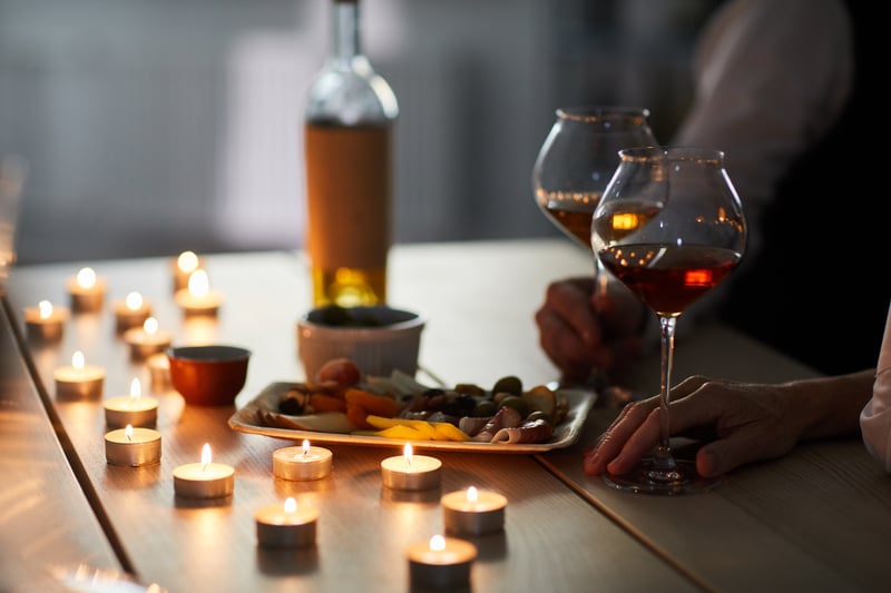 Mesa para o dia dos namorados decorada com diversas velas e com um prato de petiscos, uma garrafa de vinho e duas taças servidas.