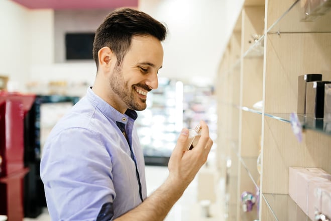 hombre feliz eligiendo perfume masculino para comprar en la tienda