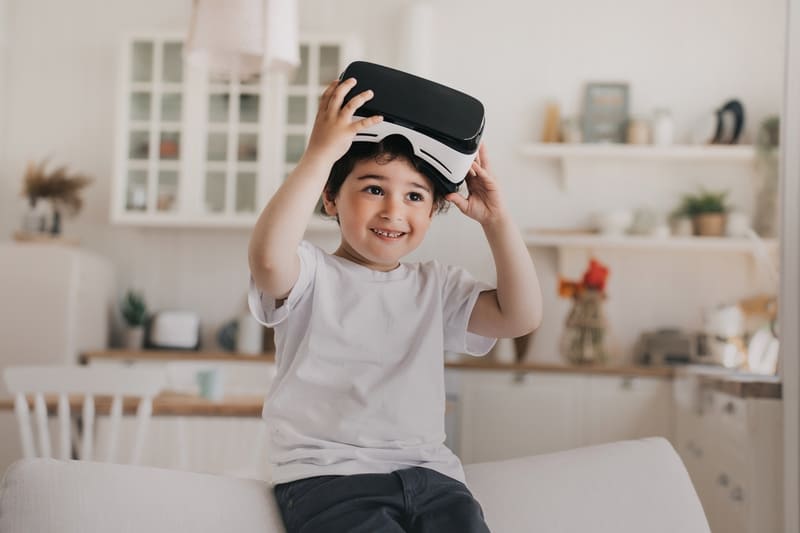 menino feliz usando oculos de realidade virtual na cozinha