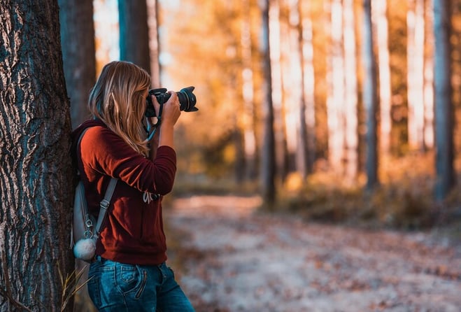 mujer sacando fotos en el bosque