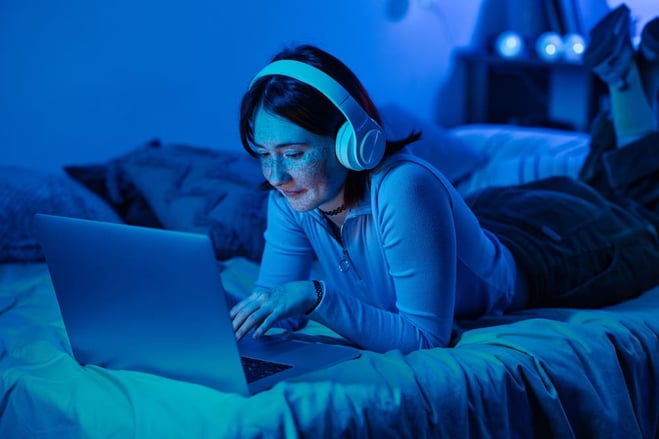 mujer viendo videos de youtube en su notebook desde su cama