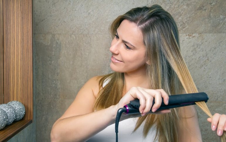 smiling-young-woman-straightening-hair-with-a-stra-2022-02-08-06-02-58-utc-1
