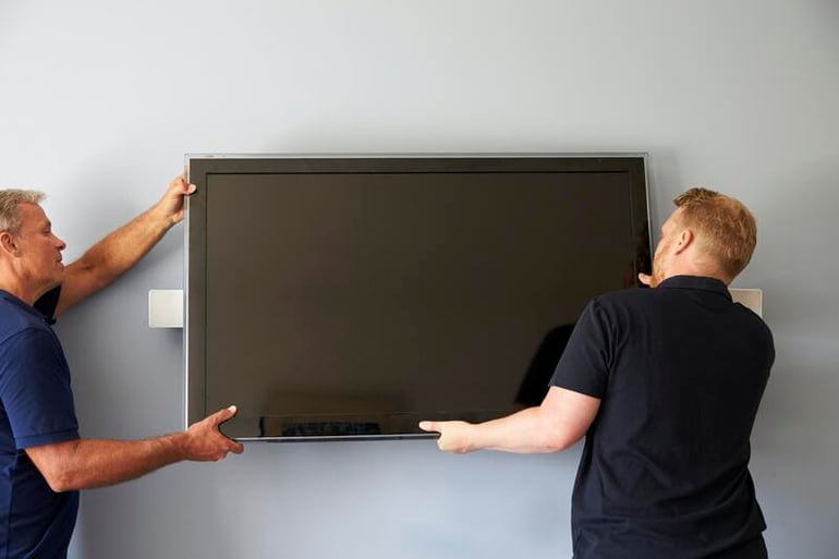 dois homens instalando uma tv