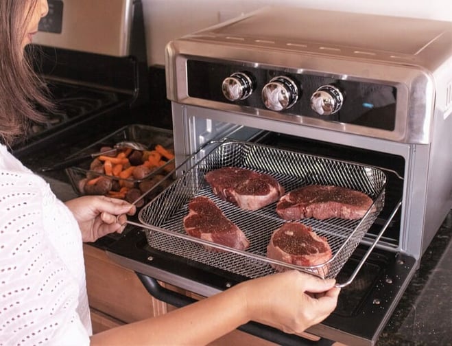 mujer cocinando carne en la freidora horno