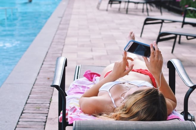 mulher deitada na beira da piscina tomando sol para bronzear a pele