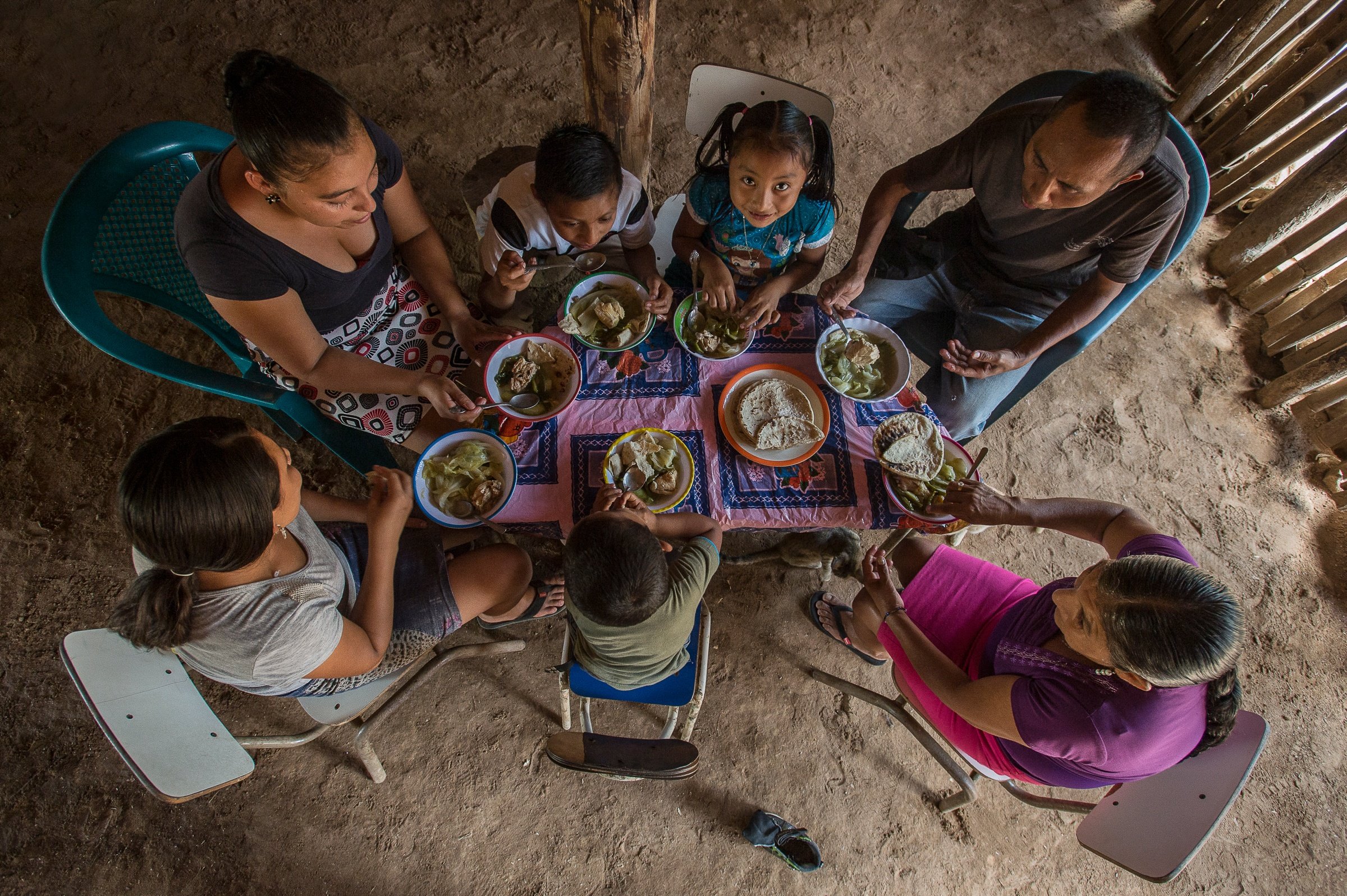 família comendo em mesa simples numa casa de pau
