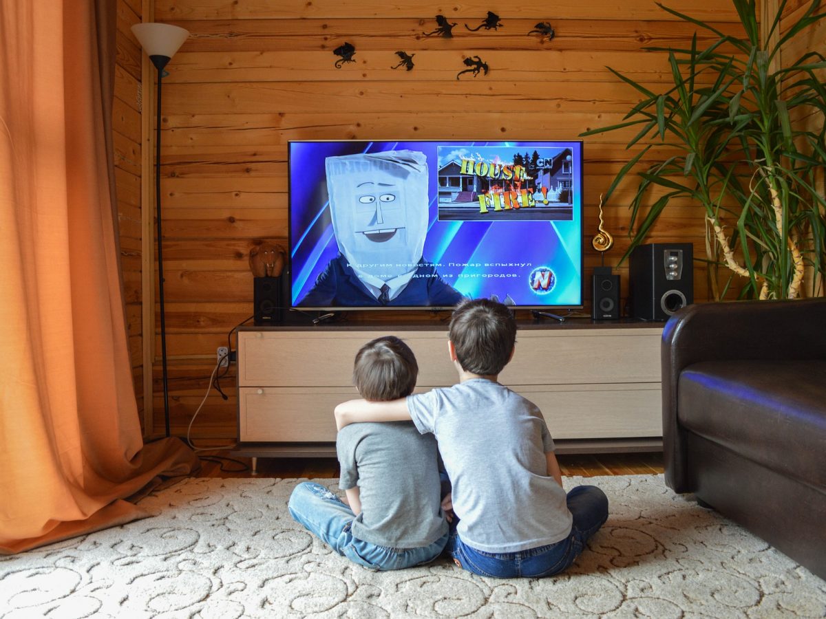 Crianças sentadas no tapete da sala assistindo Smart TV