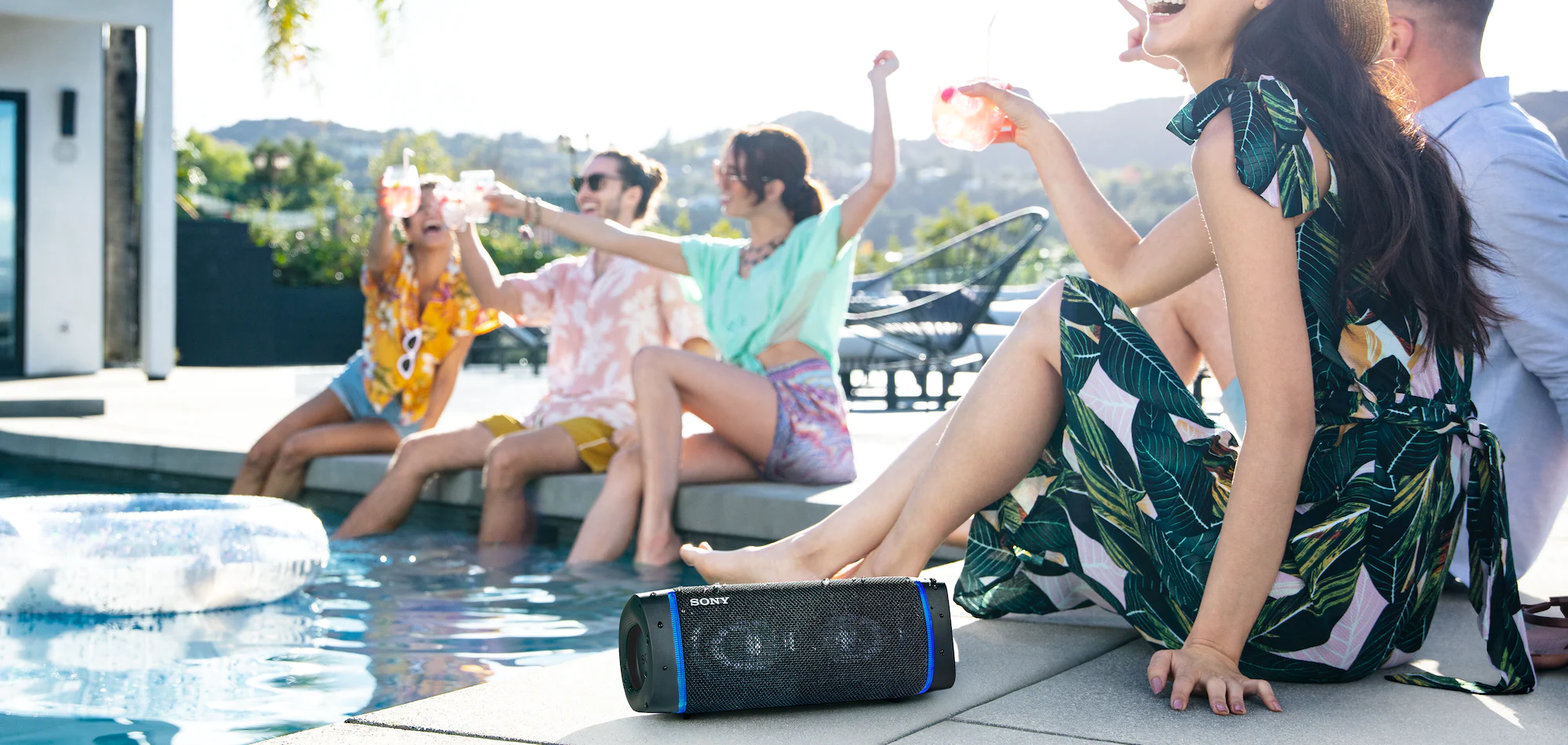 grupo de amigos curtindo um som na beira da piscina com o speaker sony srs-xb33 waterproof